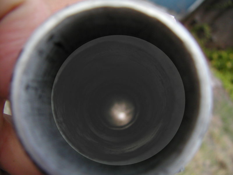 A really dark peek into the breech.  Graphite grease didn't help by making everything black.  Lightened it up some in the Gimp.  Reducer, piston cylinder, barrel breech, and ring of small ports in the barrel can be seen.